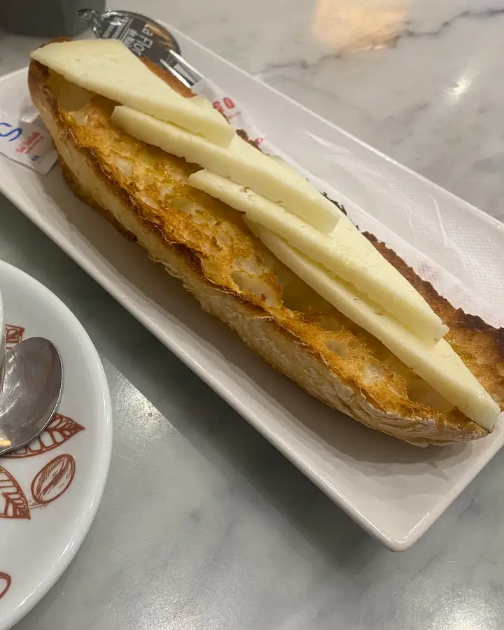 Tostada con queso manchego y un café con leche sobre una mesa de mármol